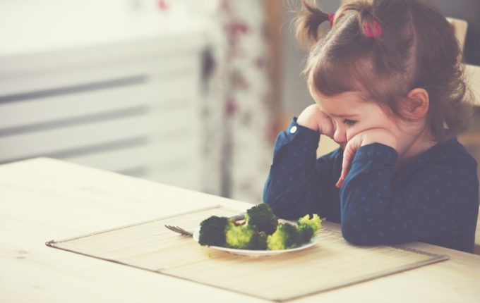 Kind schmollt vor Teller mit Brokkoli