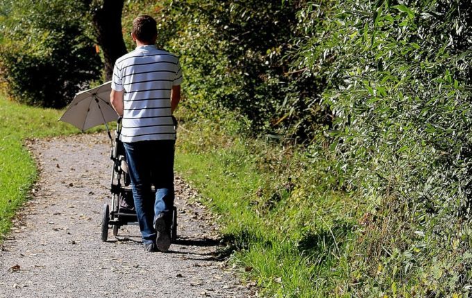 Sommertipps für Familien mit Baby und Kind - Mann fährt Kinderwagen mit Sonnenschirm