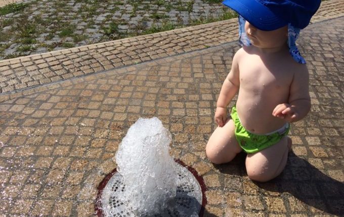Springbrunnenplatz - Kind kniet an einer Fontäne