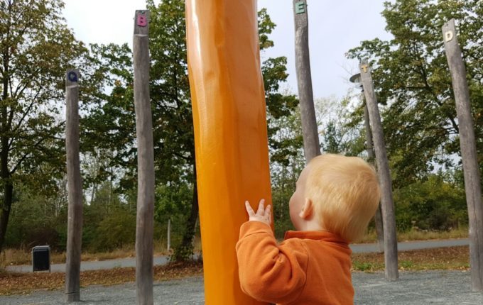 Der Buchstaben- und Balancierspielplatz in der Sebnitzer Straße - Kind am orangen Baumstamm