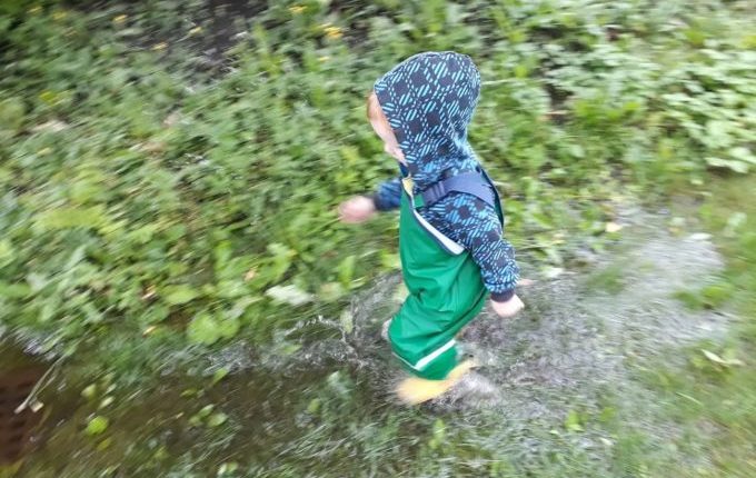 Die Regentipps - Kind rennt mit Regensachen durch große Regenpfütze