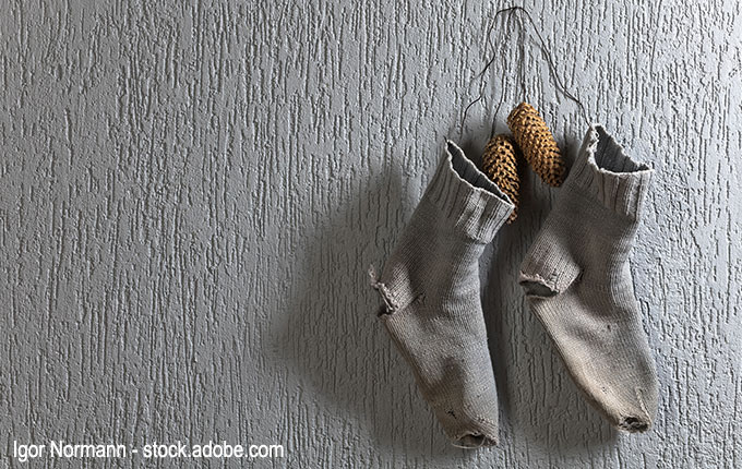 löchrige Socken und Tannenzapfen am Haken hängend