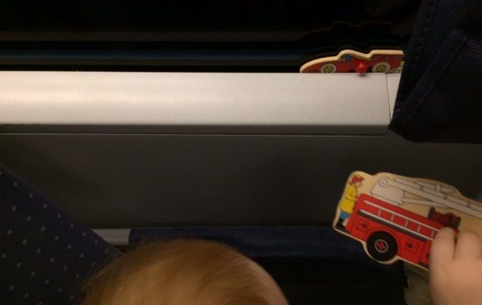 Zugfahrt mit Kleinkind - Kind spielt mit Puzzleteilen am Fenster