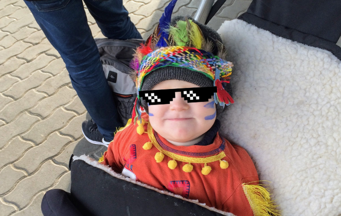 Kind in Indianerkostüm mit Kopfschmuck und Schminke