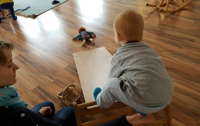 Kindercafé Sonnenkind - Kind rutscht mit Puppe