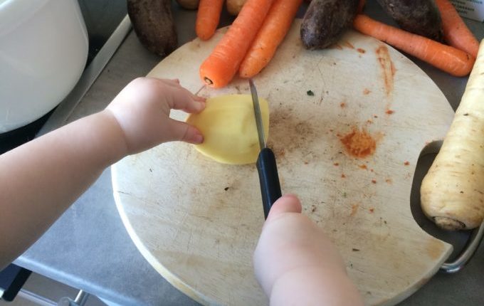 Ofengemüse - Kind schneidet Kartoffel mit Messer