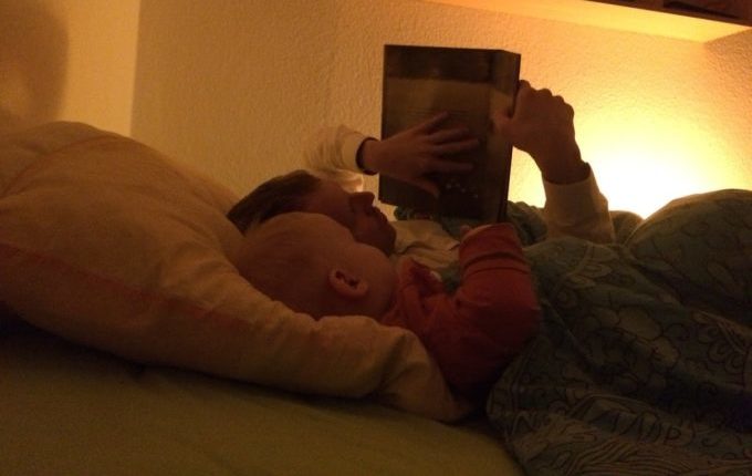 Kind liest mit Papa Buch im Bett