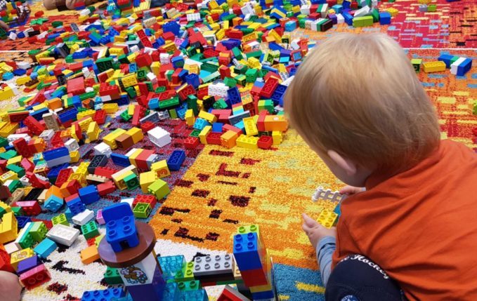 Kind spielt mit einem Berg aus Lego Duplo Bausteinen