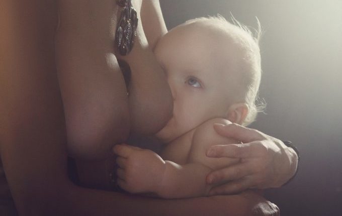 Baby spielt während des Stillens mit der Brustwarze