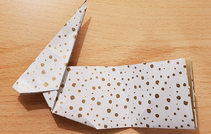 aufgefalteter Origamihase liegt auf der Seite