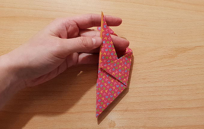 Finger nehmen Flügel vom Origamipapier in die Hand