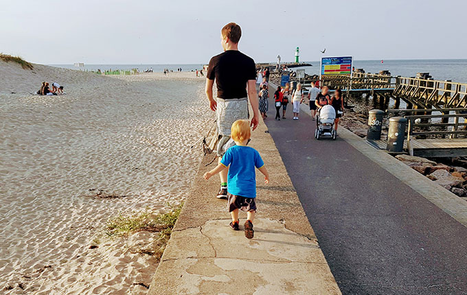 Vater und Kind balancieren auf Mauer an der Ostsee