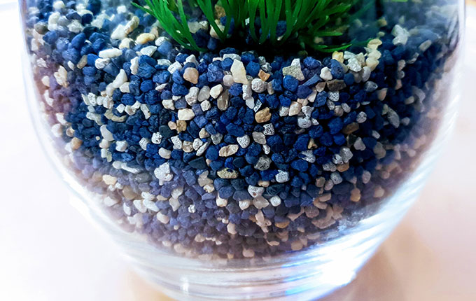 Glasvase befüllt mit blau weißem Aquariumkies