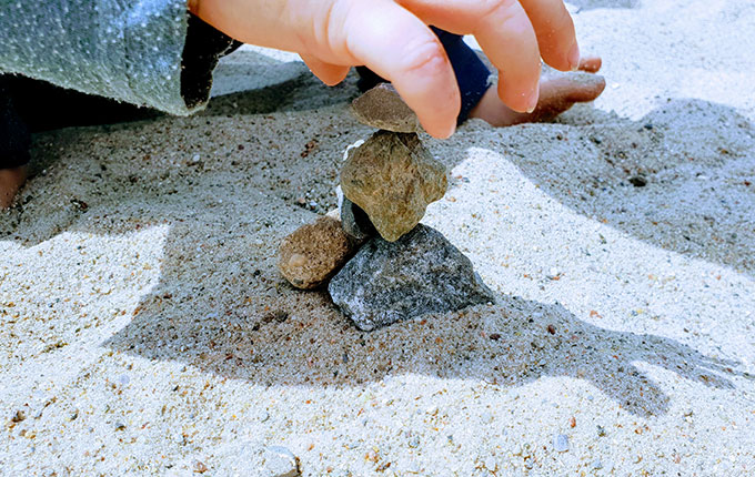 Kind stapelt kleine Steine übereinander