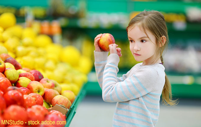 Kind prüft Apfel im Supermarkt kritisch