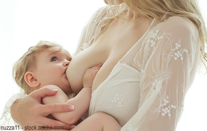 Kleinkind trinkt an der Brust im Arm seiner Mutter
