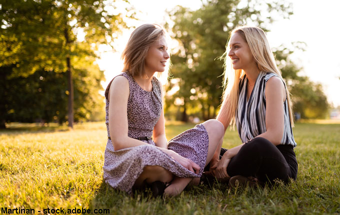 zwei Frauen sitzen im Gras und reden