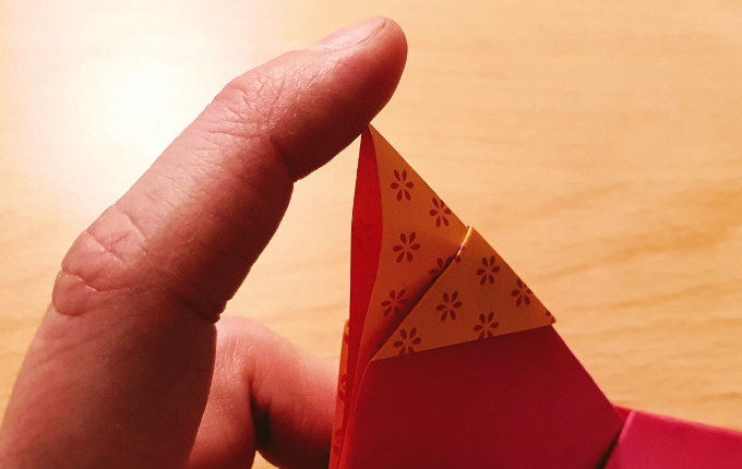 Finger knickt Spitze von Origami Huhn