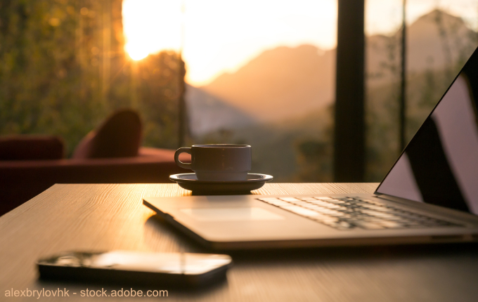 gemütlicher Arbeitsplatz mit Laptop, Telefon, Tasse und schönem Ausblick