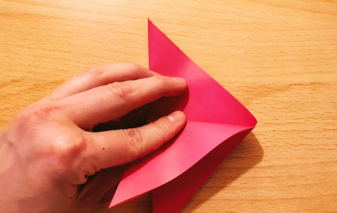 Hand faltet Origami Flügel nach unten links